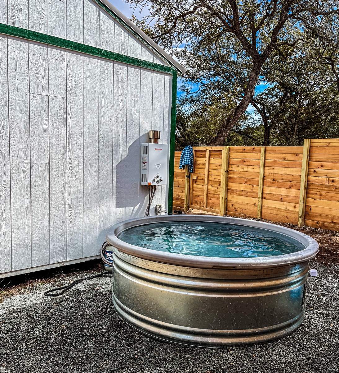 Stock tank pool beside the white casita in a cedar-fenced outdoor area